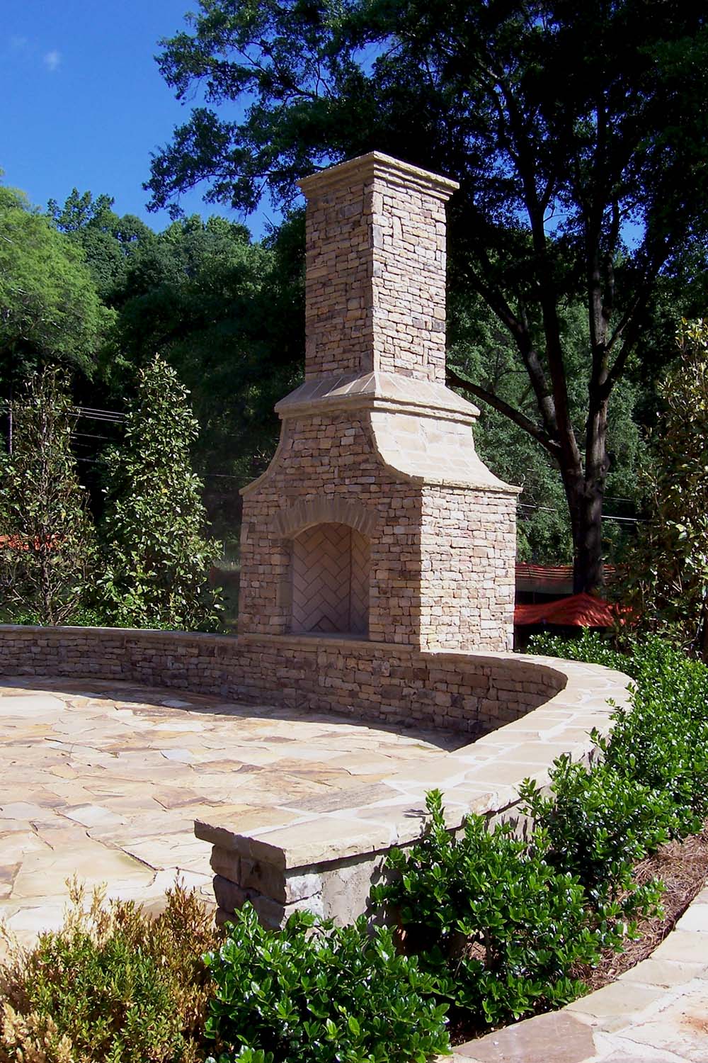 Arched front outdoor fireplace on wall, full herringbone